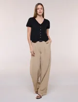 Cardigan corto de tejido de punto fino con hilo brillante de lurex y destellos metalizados. Presenta escote en V pronunciado, mangas cortas, cierre frontal con botones a tono y ruedo con terminación en pico en el frente.