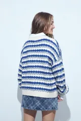 Cardigan de tejido de punto con diseño de rayas horizontales en tonos azul, gris y crema. Presenta escote en V, cierre frontal con botones grandes y mangas largas con puños anchos acanalados.