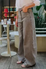 Pantalón de jean corte wide leg en color gris lavado, con tiro alto y cierre frontal con botón y cremallera.