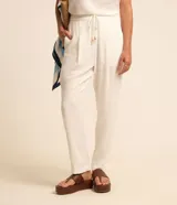Pantalón fluido Marfinno modelo pijama, color blanco, confeccionado en viscolino. Cuenta con cintura elástica en la espalda, lazo de ajuste, pliegues frontales y bolsillos laterales.