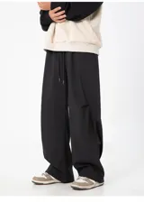 Pantalón cargo negro de corte ancho y holgado, con cintura elástica y cordón ajustable. Presenta detalles de corte o solapa en la parte trasera de las pantorrillas.