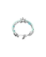 Pulsera de diseño náutico con hilo de seda color turquesa, intercalado con cuentas metálicas plateadas y cristales facetados en tono azul. Presenta un dije central en forma de estrella de mar plateada y cierre de mosquetón con placa de marca.