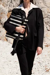 Blazer negro con tres botones en la delantera, dos bolsillos con solapa y cuello agregado estilo camisero color crema.