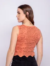 Top corto color salmón con estampado abstracto en marrón, sin mangas, con cuello redondo y terminación ondulada en el ruedo.