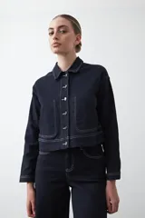 Campera de algodón color azul marino, de silueta recta y corta, con costuras a la vista en contraste blanco. Presenta botonadura frontal y bolsillos aplicados.