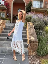 Vestido tejido en lurex color plateado, con diseño geométrico en cuero en el frente y flecos en el ruedo. Breteles finos de cuero con tientos plateados.