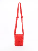 Mochila pequeña acolchada color rojo con patrón de rombos. Tiene solapa con cierre magnético y correa de hombro acolchada.