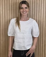 Blusa blanca de lino, con cuello redondo y mangas cortas abullonadas con frunces en los hombros.