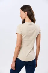 Remera polo de algodón color beige con mangas cortas, escote en V y cuello camisero. Presenta delicados mini bordados florales distribuidos en toda la prenda.