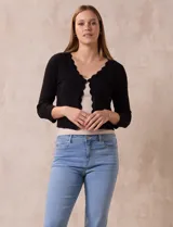 Cardigan tejido en hilado fino color blanco, marca Cable & Gauge. Abertura central con broche interno y terminación ondulada.