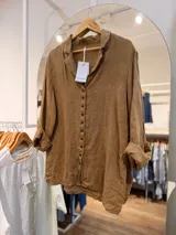 Camisa de lino gris oscuro con cuello solapa, mangas largas remangadas y cierre frontal de botones marrones.