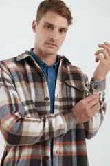Sobrecamisa de hombre con diseño a cuadros en tonos marrón, beige y blanco. Confeccionada en tejido peludito suave, con cuello clásico, cierre frontal con botones, bolsillo superior y mangas largas con puños abotonados.
