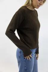 Sweater azul marino de punto con diseño de trenzas o espigas en relieve, cuello redondo y mangas largas con puños y dobladillo acanalados.