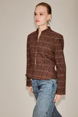 Blazer de cuello subido y manga larga, con diseño peplum en el bajo y cierre frontal con botones. Confeccionado en tejido texturizado a cuadros.