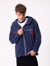 Campera de polar con cierre frontal, capucha ajustable y diseño con bloques de color azul marino y detalles en bordó. Presenta el logo de la marca bordado en el pecho.