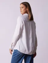 Camisa color verde oliva de lyocell, marca Cyrus. Tiene cuello con solapa, abertura central con botones, mangas 3/4 regulables con presilla y botón, y dos bolsillos delanteros aplicados.