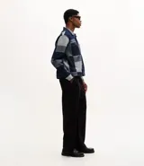 Campera de jacquard de algodón con diseño patchwork de cuadros en tonos azules. Presenta cuello inglés, cierre frontal con botones metálicos, mangas largas y bolsillos delanteros.