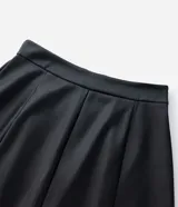 Falda midi de corte evasé confeccionada en cuero sintético (PU) de color negro. Presenta cintura estructurada con pasacintos y diseño de paneles verticales que aportan fluidez a la prenda.