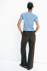 Jeans de tiro medio y corte recto, color marrón chocolate. Presenta un diseño de cinco bolsillos y detalles laterales con tejido de crochet a tono a lo largo de las piernas.