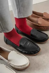Mocasines de cuero color dorado con acabado texturizado, diseño clásico de punta redondeada y costuras visibles en el empeine. Cuentan con suela plana y flexible.