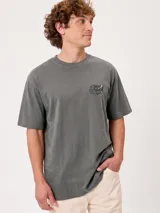 Remera oversize color beige de manga corta, con gran estampa colorida en la espalda con diseño de mapa de playa y la inscripción "Rusty County".