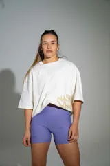 Remera oversize de algodón color off-white, con mangas cortas amplias y cuello redondo. Presenta un pequeño estampado en el centro del pecho y un diseño gráfico más grande en el lateral inferior.