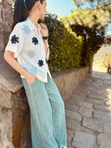 Camisa blanca con bordados de flores negras, de corte oversized y mangas cortas.