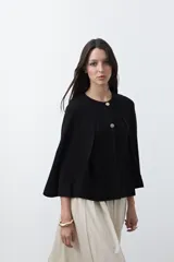 Saco tipo capa de punto color negro, con silueta fluida, corte amplio y cierre frontal con dos botones dorados.