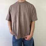 Remera marrón de corte boxy y manga corta, con gran estampado en la espalda en color celeste con el texto "MDW CLOTHING" y tipografía complementaria.