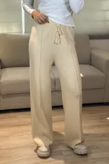 Palazzo de punto en color beige, con cintura elástica y cordón ajustable. Presenta un diseño de pierna ancha con costuras verticales decorativas en el frente.