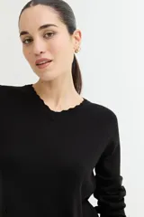 Sweater rosado de tejido de punto con escote en V y mangas largas con puños acanalados. El ruedo también es acanalado y presenta un detalle de crochet.