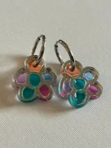 Par de aros colgantes con forma de flor, con pétalos de acrílico de colores translúcidos (naranja, verde azulado, fucsia, lila y celeste) y argollas de metal plateado.