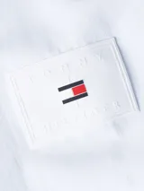 Campera blanca de Tommy Hilfiger con capucha, cierre frontal con cremallera, dos bolsillos laterales y logo de la marca bordado en la manga.