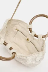 Bolso de mano tipo media luna con apliques nacarados, doble asa circular de madera y asa bandolera de cadena extraíble. Incluye forro y bolsillo interior.