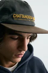 Gorra de algodón negra con visera plana de color marrón oscuro. Presenta bordado frontal en hilo dorado con el texto "CHATTANOOGA BEAT THE LANGUAGE OF JAZZ SINCE 1920".
