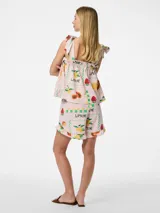 Short de tiro alto con cintura elástica y detalle de volados en el ruedo. Presenta un diseño estampado con motivos frutales y soles sobre fondo rosado, con un corte holgado y fresco.