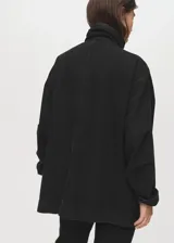Anorak de estilo utilitario confeccionado en tejido de algodón tipo denim, con diseño oversize, cuello embudo, cierre frontal de cremallera y botones a presión, y cuatro bolsillos de parche con solapa en la parte delantera.