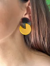 Aros colgantes con forma de círculos combinados, uno color marrón carey y otro color mostaza.