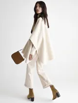 Saco tipo capa color beige con diseño espigado, cuello alto y cierre con un botón.