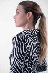 Vestido midi de corte ajustado, con estampado animal print tipo cebra en blanco y negro, cuello camisero, escote en V y cierre frontal con botones dorados.