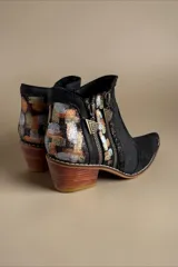 Botas de caña corta de cuero negro jaspeado, pintadas a mano con arte en tonos dorados, plateados y marrones en la parte trasera. Cuentan con doble cierre lateral con tiradores metálicos personalizados, puntera fina y taco cuadrado de madera.