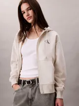 Buzo con capucha, cierre frontal de cremallera y bolsillos canguro, de color beige, con logo monograma de Calvin Klein bordado en el pecho.