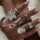 Set de anillos plateados con diferentes diseños: anillo liso, anillo con forma de flor, anillo con forma irregular, anillo con perla, anillo con piedras de colores y anillo con textura ondulada.