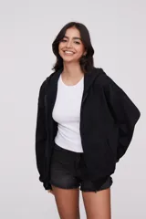 Campera canguro de algodón color negro, con capucha, cierre frontal completo y bolsillos delanteros tipo ojal. Diseño de mangas largas y calce holgado.