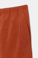 Pantalón tipo palazzo de corte recto y tejido fluido, color naranja. Presenta cintura elástica con cordón ajustable y bolsillos laterales.
