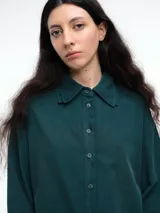 Camisa oversize de lyocell color tostado, con cuello clásico, cierre frontal de botones y mangas largas con puños anchos. Presenta un diseño de corte relajado con caída fluida.