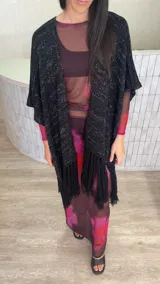 Ruana de tejido de punto color crema con diseño de líneas horizontales caladas y terminación con flecos en el ruedo.