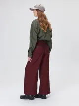 Pantalón sastrero de tiro medio, pierna ancha y corte recto, color bordó con finas rayas verticales y detalles de vivos a contratono en la pretina y el frente.