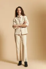 Pantalón de corte recto y tiro medio, color marrón, con detalle de tachas metálicas a lo largo de las costuras laterales y tajos en el ruedo.