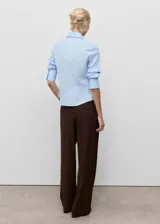 Camisa de corte entallado confeccionada en popelín de algodón con elastano. Presenta cuello camisero clásico, cierre frontal con botones y mangas largas con puños abotonados.